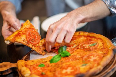 Bir dilim pizza alan adamın ellerini yakın plan çek.