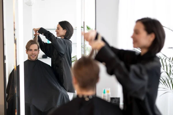 Peluquería de cabello oscuro trabajando en un corte de pelo elegante —  Fotos de Stock