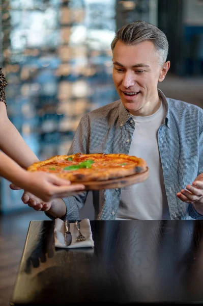 Pizza yiyen ve heyecanlı görünen bir adam. — Stok fotoğraf