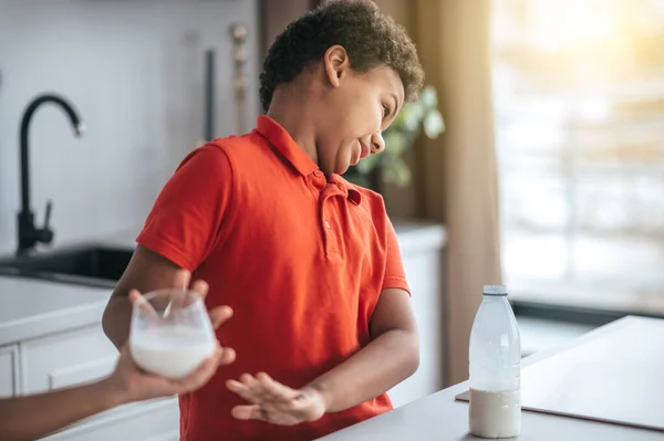 Un chico con camisa roja que se niega a tomar leche — Foto de Stock