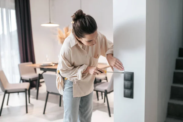 A young woman checking the power socket and looking involved — Stock Photo, Image