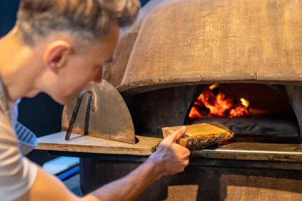 A man making fire in the oven in italian bakery — Stock Photo, Image