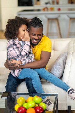 Gülen adam, küçük kızı kucaklıyor.