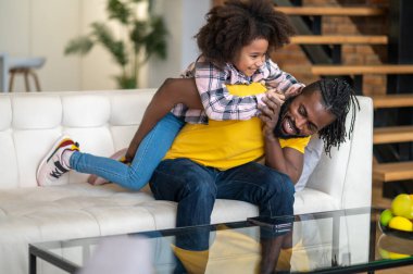 Baba kızını kucağına alıp koltuğa oturuyor.