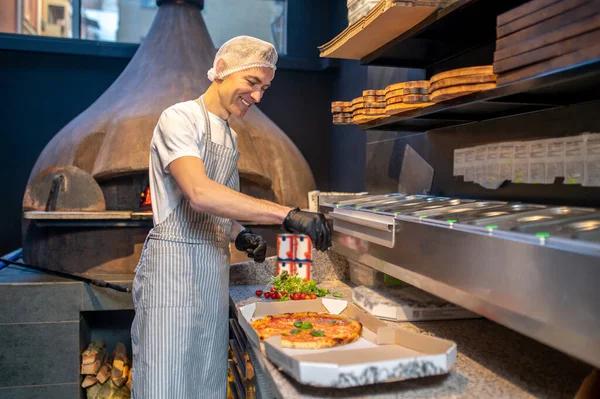 Önlüklü ve bereli bir şef pizza hazırlıyor. — Stok fotoğraf