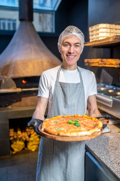 Önlüklü ve bereli bir şef pizza hazırlıyor. — Stok fotoğraf