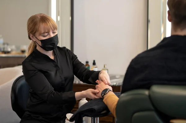 Косметолог делает массаж рук клиенту-мужчине — стоковое фото