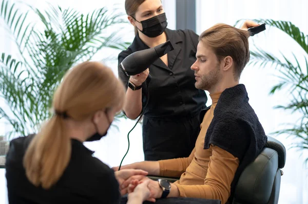 Парикмахер в защитной маске укладки волос для клиента — стоковое фото