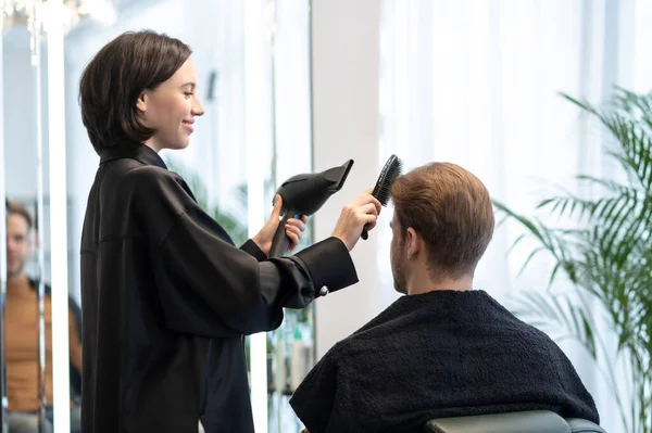 Koyu saçlı kadın güzellik salonunda erkek bir müşteriyle çalışıyor. — Stok fotoğraf