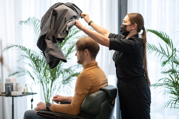 Uzun saçlı kuaför güzellik reyonunda erkek bir müşteriyle çalışıyor. — Stok fotoğraf