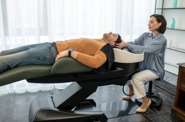 Güzellik uzmanı saç tedavi prosedürleri sırasında baş masajı yapıyor.