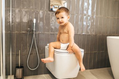 Seramik tuvalette oturan sakin bir çocuk.
