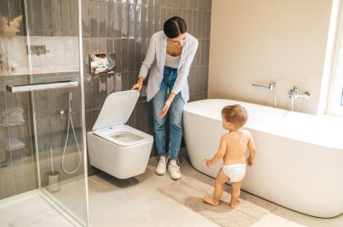 Caring female parent toilet-training her baby boy clipart