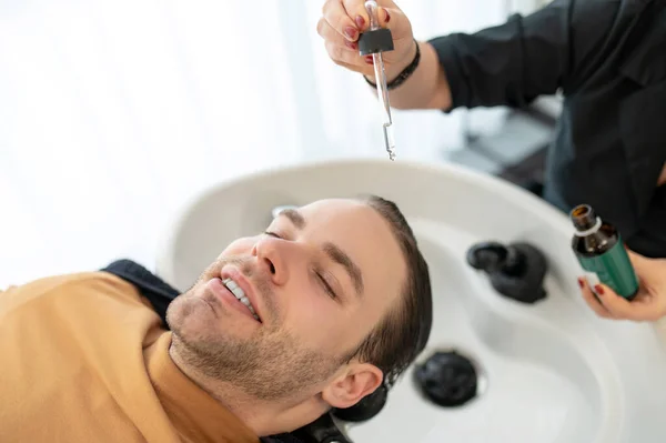 Esteticista aplicando gotas revitalizantes para el cabello en la cabeza de los clientes —  Fotos de Stock