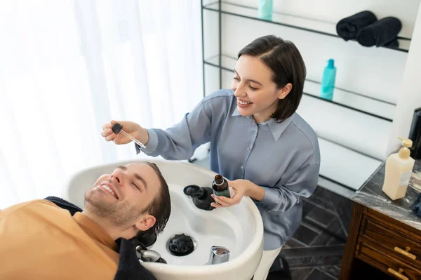 Esteticista aplicando gotas revitalizantes para el cabello en la cabeza de los clientes —  Fotos de Stock