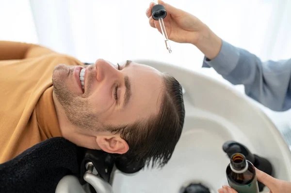 Beautician applying hair serum on mans head — Stock Photo, Image