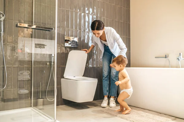 Vårda unga mor toalett-utbildning hennes manliga barn — Stockfoto