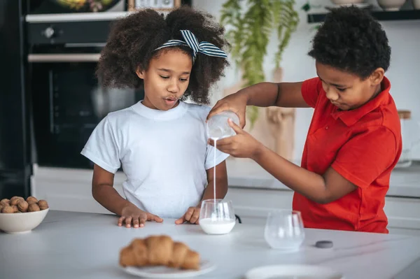 Zwei Kinder in der Küche mit Milchgläsern in der Hand — Stockfoto