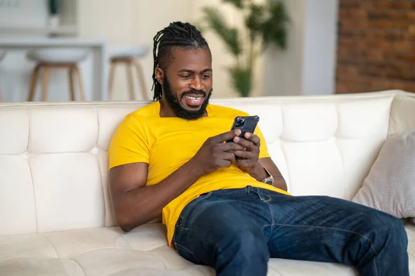 Mann sitzt auf Sofa und schaut aufs Smartphone — Stockfoto
