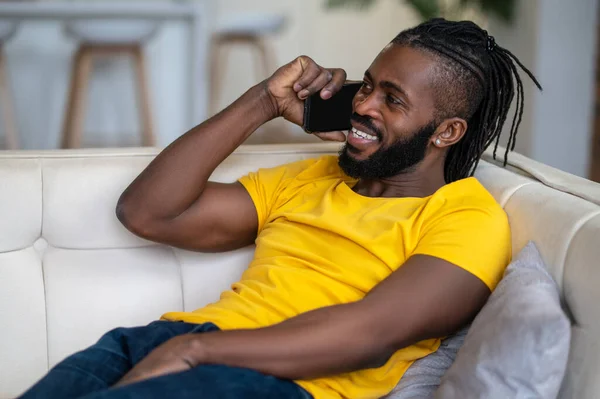 Hombre feliz con teléfono inteligente cerca de la oreja en el sofá — Foto de Stock