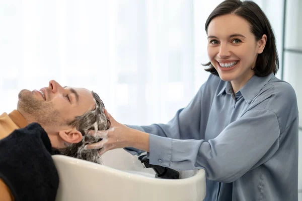 Hombre cliente sentado en la silla en el salón de belleza y tener su cabello lavado —  Fotos de Stock