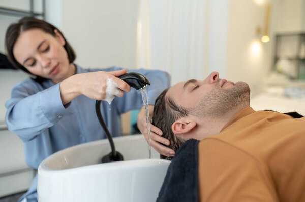 Hairdresser washing hair to the male client in a beauty salon