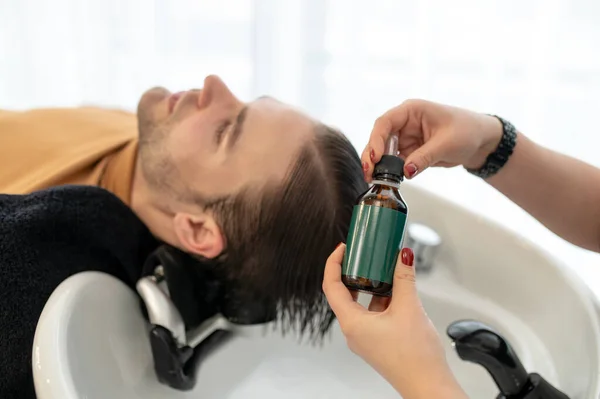 Esteticista aplicando gotas revitalizantes para el cabello en la cabeza de los clientes — Foto de Stock