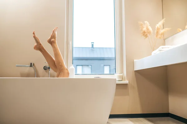 入浴中に下肢を空中に持ち上げる女性 — ストック写真