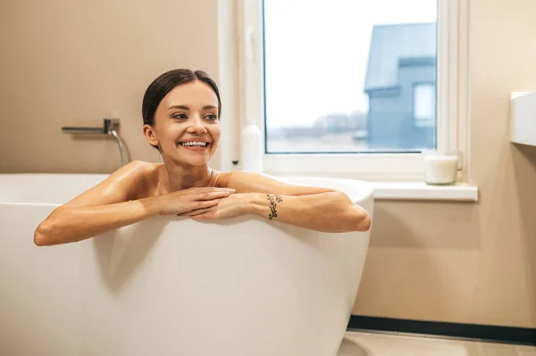 Glückliche junge Frau sitzt in der Badewanne — Stockfoto