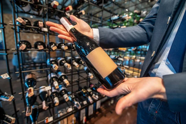 A man in a wine store with lots of bottles with wine — Stock Photo, Image