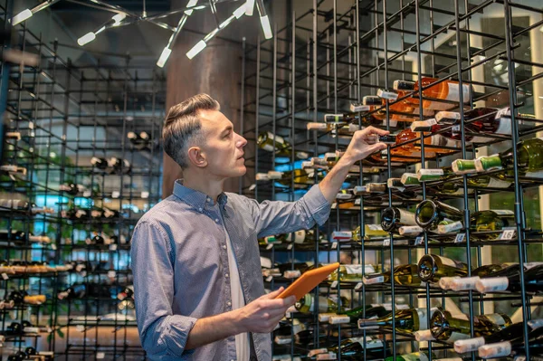 Şarap dükkanında elinde bir sürü şarapla bir adam. — Stok fotoğraf