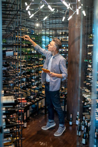 Bir şarap dükkanı sahibi revizyon yapıyor ve meşgul görünüyor. — Stok fotoğraf
