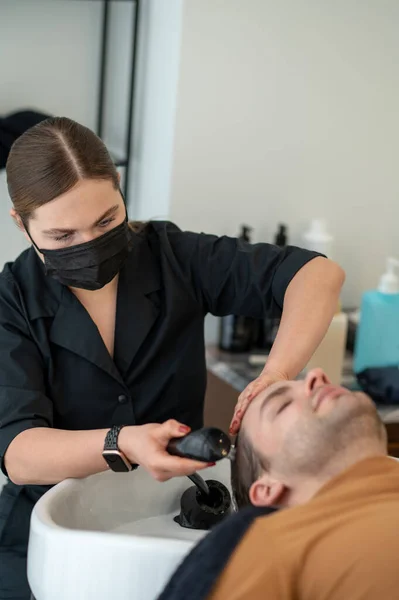 Parrucchiere femminile che lava capelli al cliente — Foto Stock