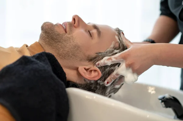 Jovem sentado no chait, tendo massagem na cabeça e olhando relaxado — Fotografia de Stock