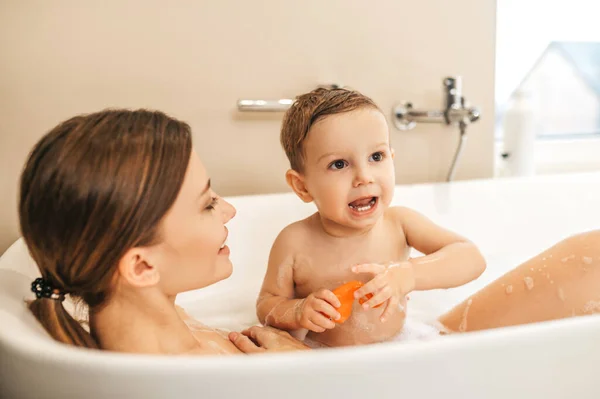 Jovem mãe tomando um banho com seu bebê menino — Fotografia de Stock