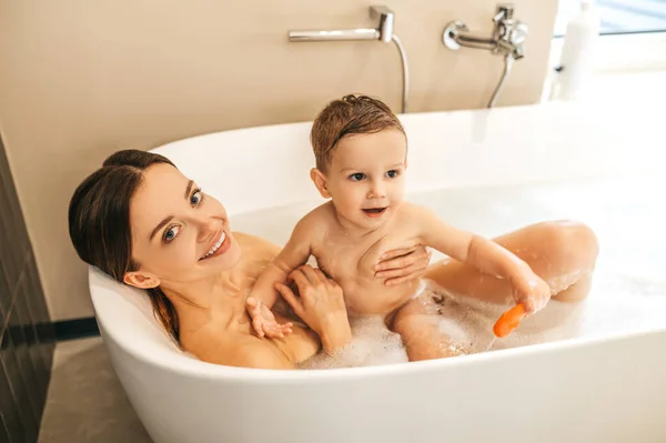 Glückliche junge Mutter beim Baden mit ihrem Kind — Stockfoto