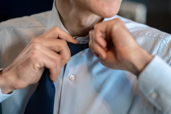 Een zakenman in een blauw shirt die zijn das losmaakt. — Stockfoto