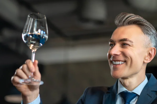 Elegancki mężczyzna w garniturze ze szklanką wina w rękach — Zdjęcie stockowe