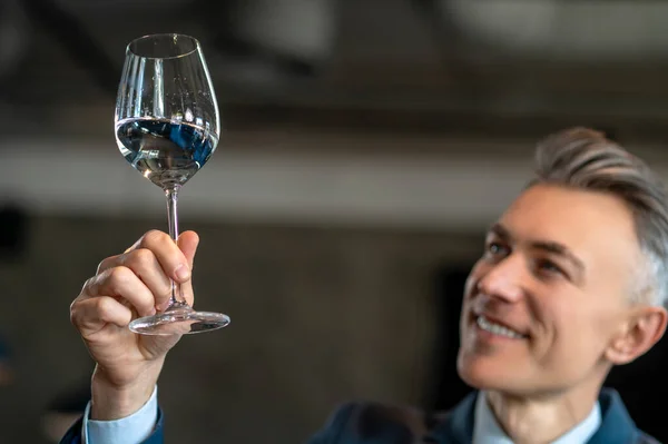 En elegant man i kostym med ett glas vin i händerna — Stockfoto