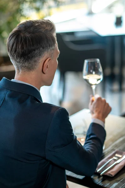 Een elegante man in een pak met een glas wijn in handen — Stockfoto
