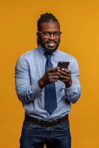 Hombre de negocios alegre con su teléfono celular de pie en el interior — Foto de Stock