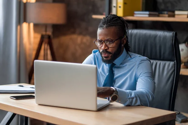 Homem de negócios concentrado em óculos usando seu laptop — Fotografia de Stock