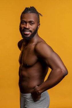 Gömleksiz genç atletik adam kaslarını gösteriyor.