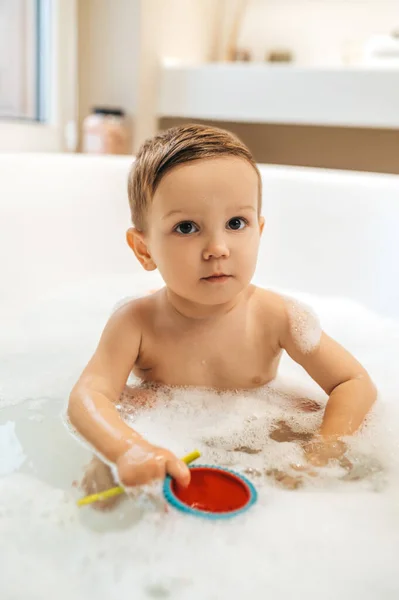 Menino com brinquedos de borracha sentado no banho — Fotografia de Stock