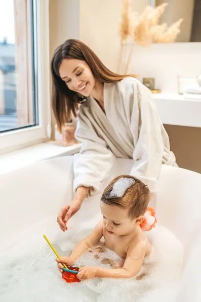 Vårdande mor badar sitt barn i badrummet — Stockfoto