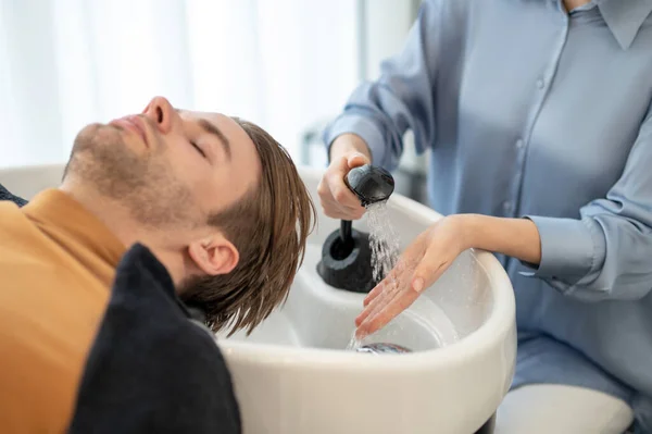 美容師は彼女の男性クライアントに髪を洗う — ストック写真