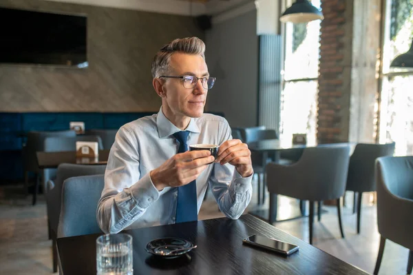 Een elegante man in brillen zittend in een café — Stockfoto