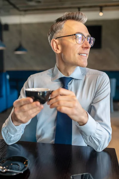 İş adamı bir kafede sabah kahvesi içiyor.