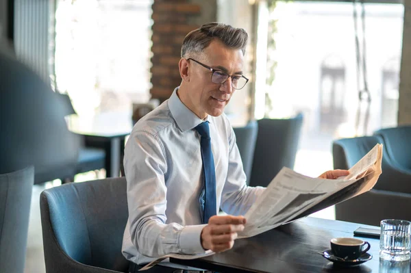 Un hombre de negocios leyendo un periódico en un café —  Fotos de Stock