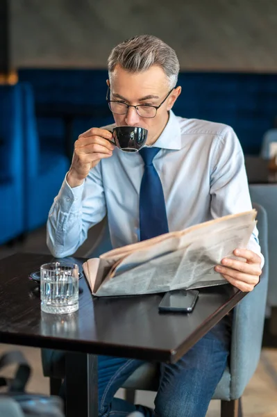 Ein Geschäftsmann liest Zeitung in einem Café — Stockfoto